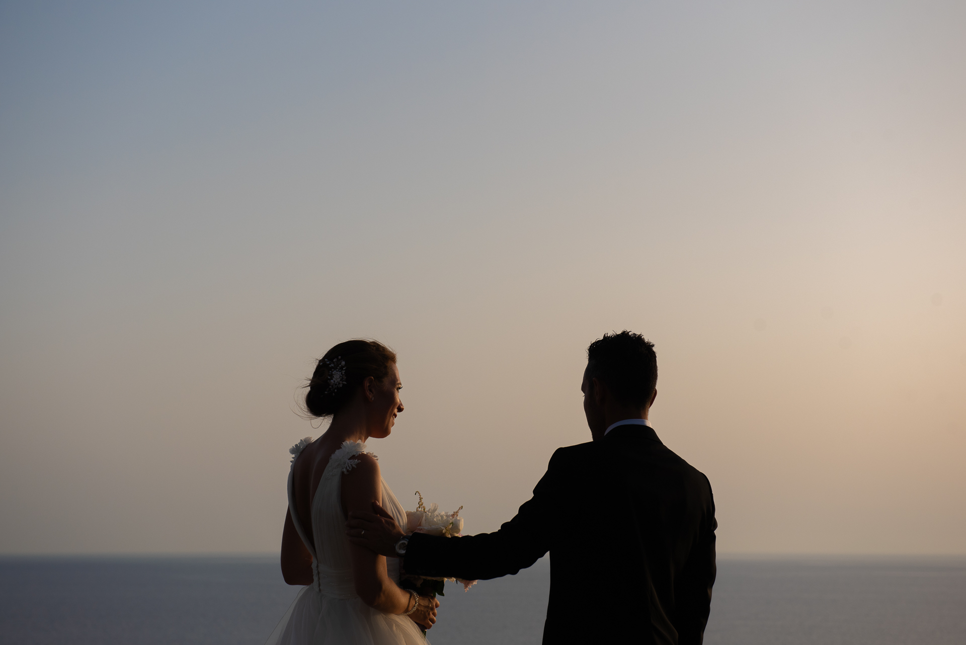 Wedding photographer Tropea Calabria — bride and groom silhouetted at sunset on the Tyrrhenian coast