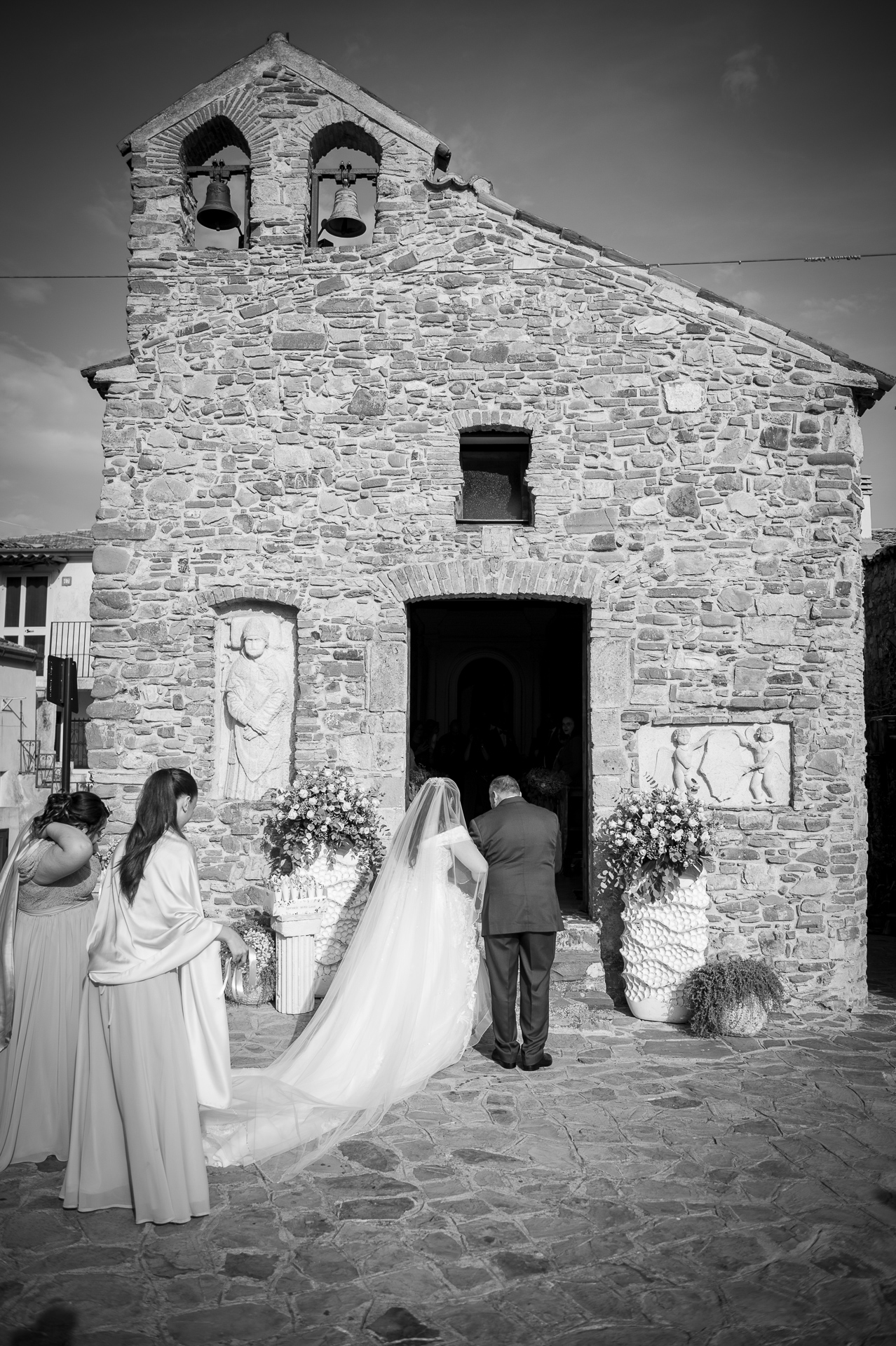 Foto verticale della sposa davanti alla chiesa: il formato stretto taglia le damigelle e parte della facciata