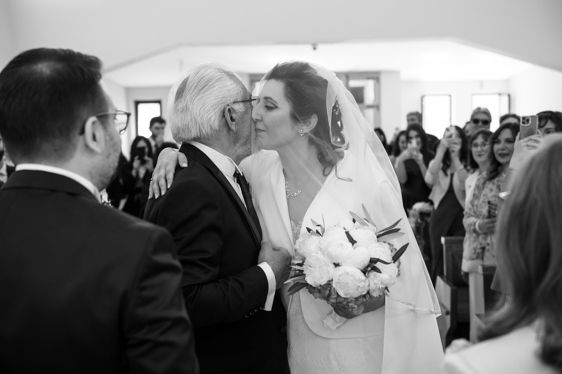 Abbraccio tra sposa e padre prima della cerimonia, fotografato in orizzontale con tutta la scena intorno